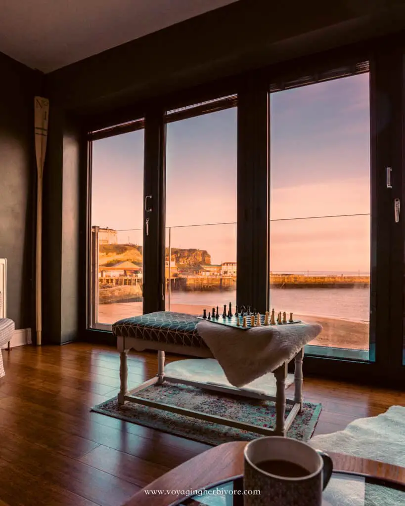 whitby flat overlooking beach and whitby harbor at sunrise with a bench and chessboard in the foreground