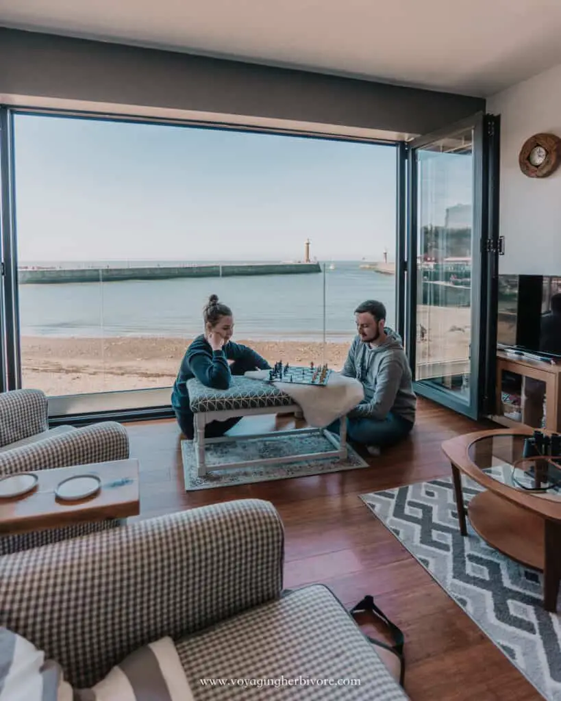 couple playing chess next to open doors overlooking the beach at whitby pier north yorkshire