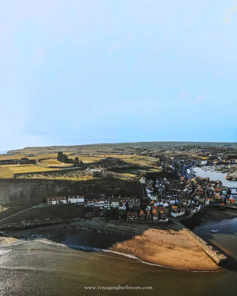 drone shot of whitby harbor and pier with whitby abbey 