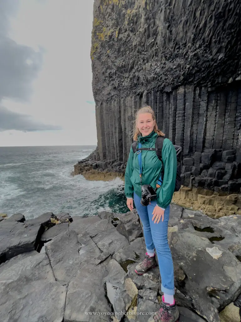 woman stands on the edge of fingal's cave